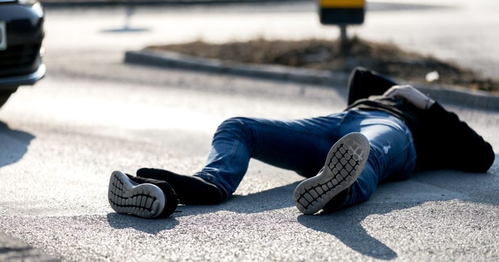 Person laying on the ground after getting hit by a car